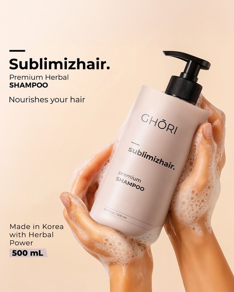 A high-quality product shot of a premium shampoo bottle held in soap-sudded hands against a clean, neutral background.