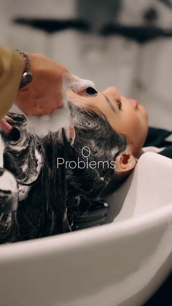 A close-up 9:16 vertical video frame showing hair being washed in a salon, overlaid with the minimal text '0 Problems'.