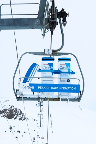 A high-concept product hero ad featuring CeraVe shampoo bottles placed on a ski lift chair against a snowy mountain backdrop.