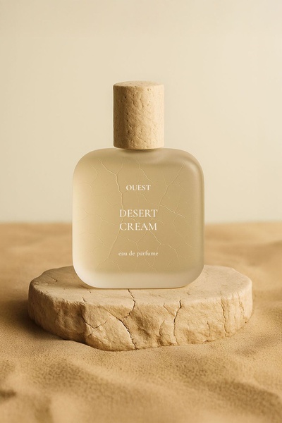 A high-end, minimalist studio shot of a perfume bottle placed on a cracked, earth-toned platform within a desert-like sandy environment.