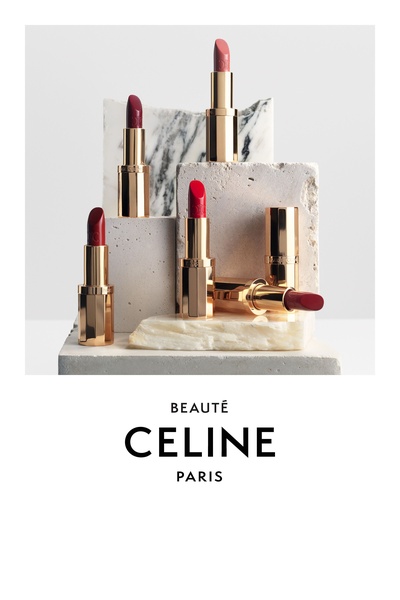 A high-end, editorial-style composition featuring multiple lipsticks in shades of red and pink arranged on stone platforms against a clean, neutral background.