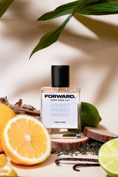 A minimalist studio shot of a perfume bottle surrounded by fresh citrus, wood, and tea elements.