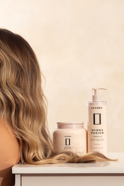 A clean, minimalist product-focused advertisement featuring the Hydra Fusion leave-in treatment and hair mask, showcasing the product alongside healthy hair.