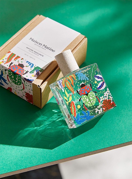 A high-contrast, professional product shot of a perfume bottle and its packaging placed on a bright green surface with natural shadow play.