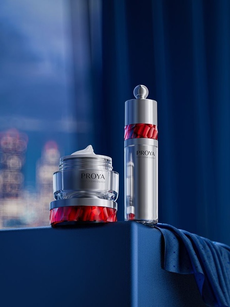 A high-end studio capture of a skin cream jar and bottle set, presented on a minimalist blue platform with a dramatic, moody lighting environment.