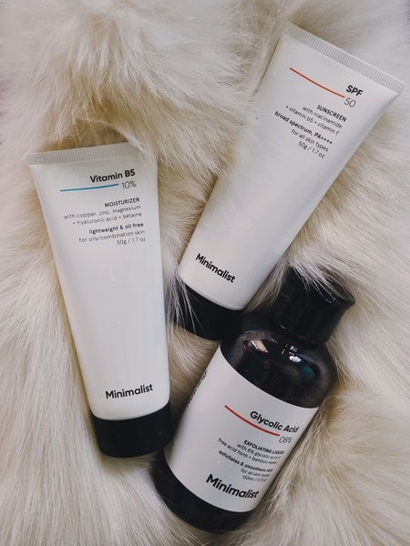 This creative displays three Minimalist skincare products—moisturizer, sunscreen, and exfoliating liquid—arranged on a high-texture fur background.