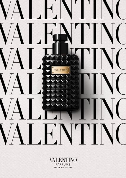 This creative showcases a premium perfume bottle centered against a high-contrast background of repeating brand text, emphasizing prestige and visual symmetry.