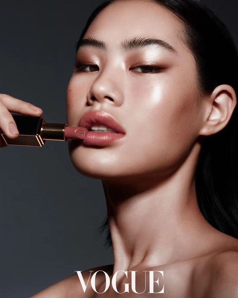 A high-fashion, minimalist portrait focusing on a lipstick product with clean lighting and neutral tones.