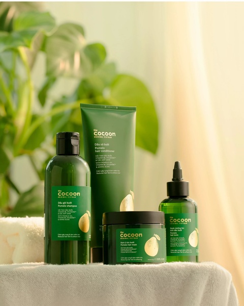 This creative showcases a complete set of pomelo-infused hair care products in a serene, natural lighting environment.
