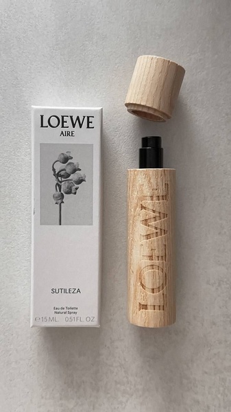 A high-quality top-down shot of a wooden perfume bottle and its corresponding packaging, highlighting a clean and premium natural aesthetic.