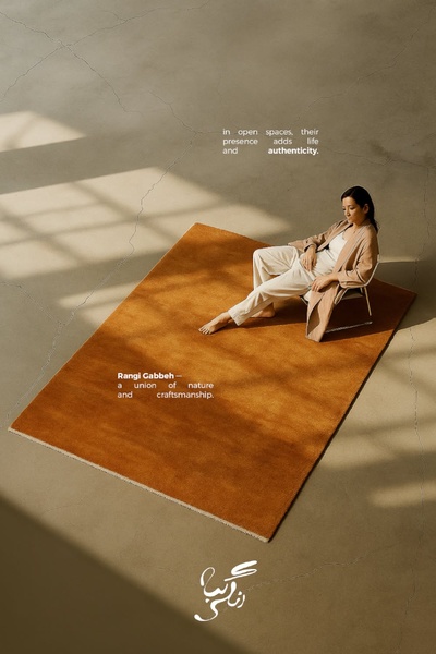 A minimalist top-down shot of a woman relaxing on a textured rug in a sun-drenched, open room to emphasize natural material quality.