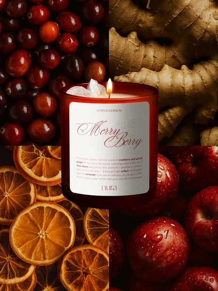 A high-quality studio hero shot of a red scented candle surrounded by raw ingredients like cranberries, ginger, apples, and dried oranges.