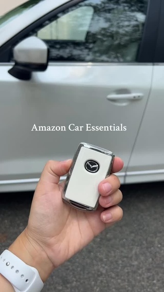 A close-up shot showing a stylish car key cover in hand against a white vehicle background, emphasizing product design.