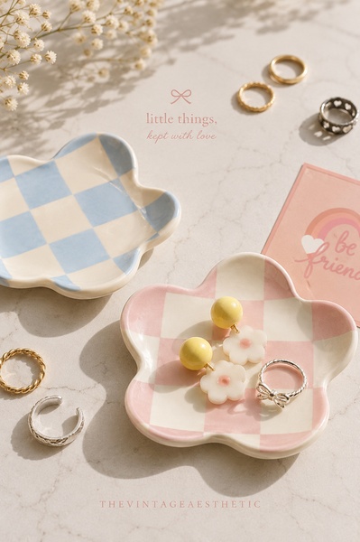 A high-key, bright lifestyle shot of a ceramic flower-shaped trinket dish holding small jewelry on a marble surface.