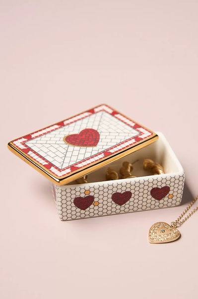 A high-end, clean product shot of a decorative jewelry box presented alongside a delicate necklace on a soft-toned background.
