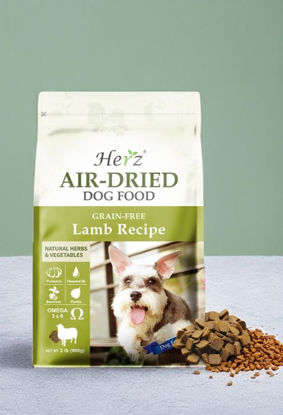 A clean, studio-lit hero shot featuring the Air-Dried Dog Food bag alongside a small pile of kibble and a friendly dog portrait.