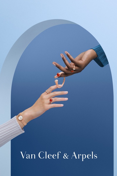This creative features an elegant, studio-style product shot of a bracelet and ring being exchanged between two hands against a blue, arched background.