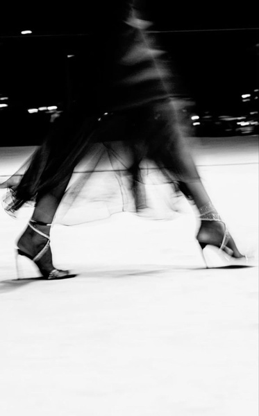A high-contrast, black and white artistic shot capturing the movement of a person wearing high heel shoes, emphasizing elegance and pace.