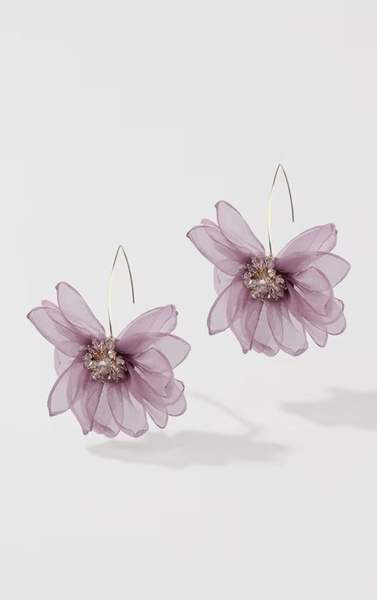 A high-contrast hero shot of a pair of purple floral-shaped earrings suspended against a clean white background.