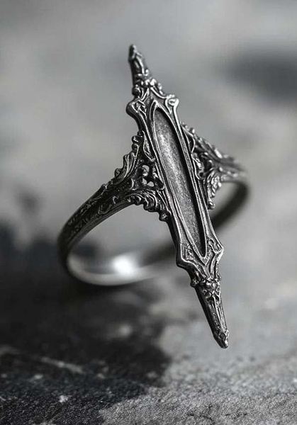 A close-up, high-detail macro shot of a weathered, gothic-style silver ring shaped like a dagger, set against a dark, textured stone background.