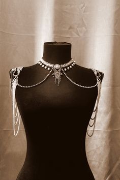 A high-contrast studio photograph featuring a shoulder-draped pearl and diamond body chain on a black mannequin.