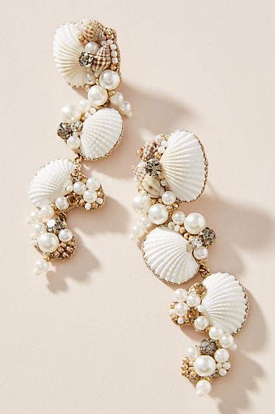 A high-definition macro shot of intricate shell and pearl earrings, emphasizing texture and delicate craftsmanship on a soft neutral background.