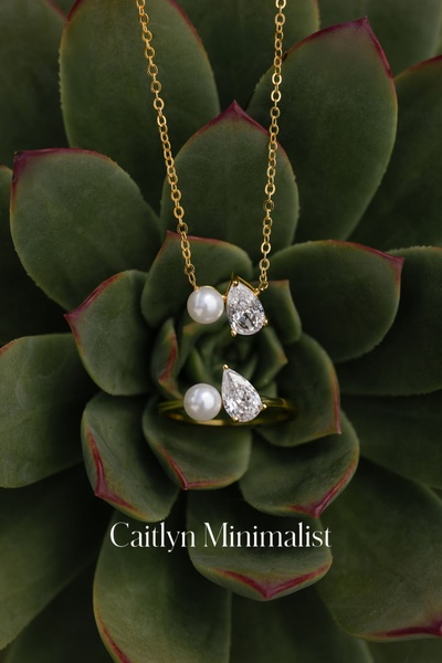 A high-contrast hero shot of a pear-cut necklace and matching ring placed inside a lush green succulent, focusing on clean, premium product presentation.
