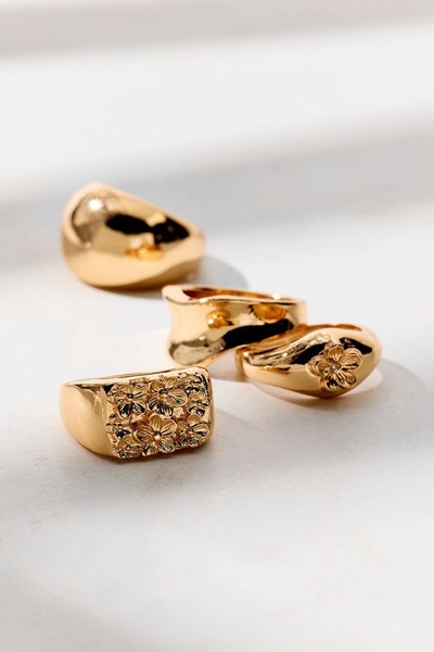 A close-up studio shot featuring a selection of gold rings in varying textures and finishes, emphasizing luxury and minimalist design.
