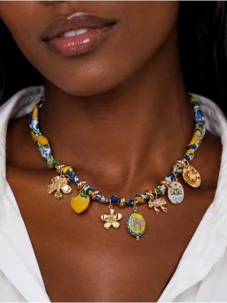 A close-up, high-fashion shot of a person wearing a vibrant charm necklace, emphasizing the intricate details and Mediterranean-inspired aesthetic.