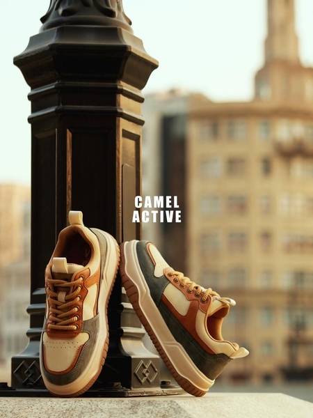 A high-quality 3:4 product hero shot of sneakers placed against a dark urban lamp post in soft evening light.
