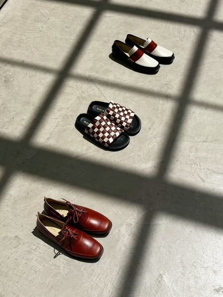 A high-contrast, top-down studio shot of three distinct footwear styles arranged on a textured concrete surface.
