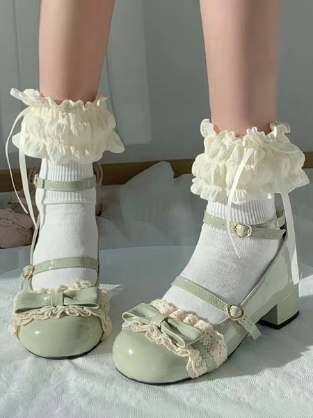 A close-up, high-angle shot of pastel green Lolita shoes paired with white frilled socks, focusing on product texture and style details.