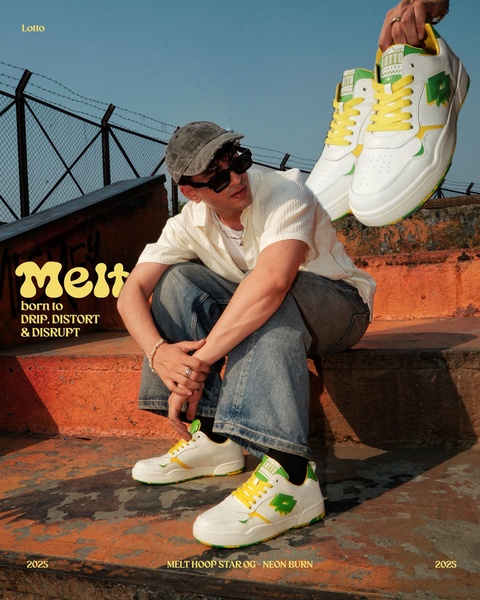A high-fashion urban sneaker campaign featuring a model posing in a gritty, industrial setting with neon-accented white shoes.