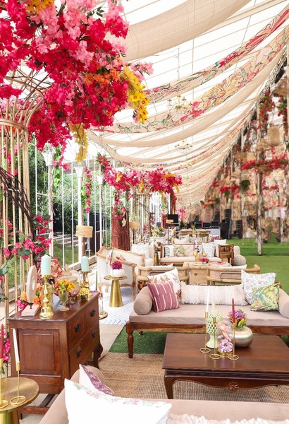 An immersive shot of a high-end event space featuring floral arrangements and elegant furniture setups under a draped canopy.