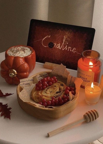A cozy, fall-themed flat lay featuring a pastry, pumpkin-shaped mug, and candles that sets a relaxing seasonal mood.