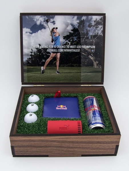 An elegant, high-end gift box featuring golf balls, a beverage, and brand accessories, designed to offer an exclusive experience.