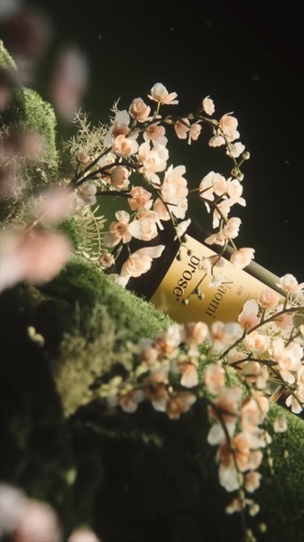 A high-end, aesthetic product shot featuring a bottle of ros) wine nested among soft pink flowers and deep green moss.