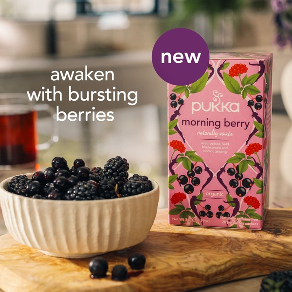 A close-up, high-quality product shot featuring herbal tea packaging next to a bowl of fresh berries to convey natural energy and organic ingredients.