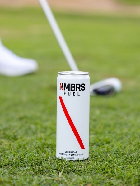 A high-contrast, clean shot of a zero sugar energy drink can placed on a manicured golf course green.