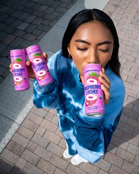 A top-down, first-person view showing a user holding and consuming a sparkling drink, emphasizing product branding and lifestyle usage.