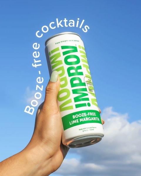 A high-contrast 4:5 shot featuring a hand holding a lime margarita can against a vibrant blue sky to emphasize a clean, refreshing brand aesthetic.