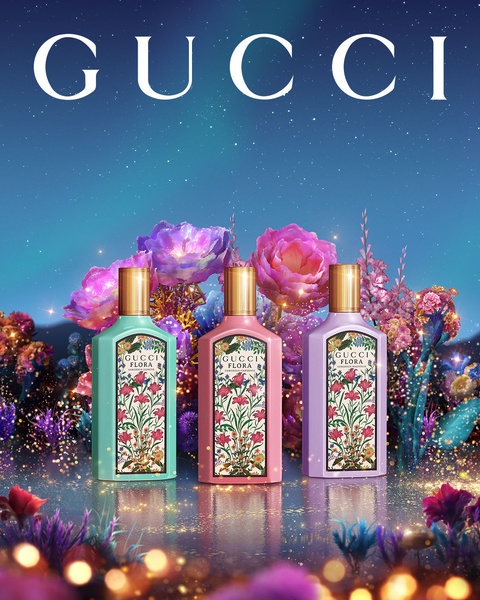Three perfume bottles positioned center-frame amidst glowing, oversized flowers and a starlit, aurora-style night sky background.