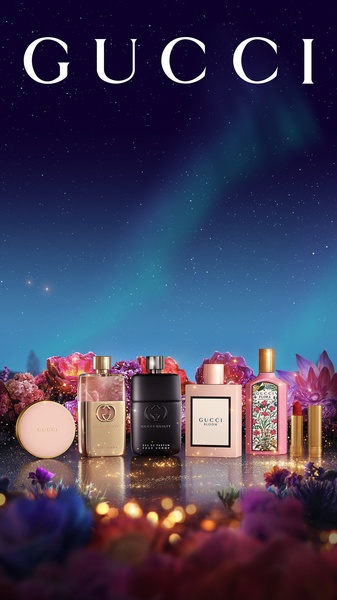 A high-end, atmospheric display of various luxury perfume and cosmetic products set against a vibrant, star-filled night sky with a subtle aurora effect.