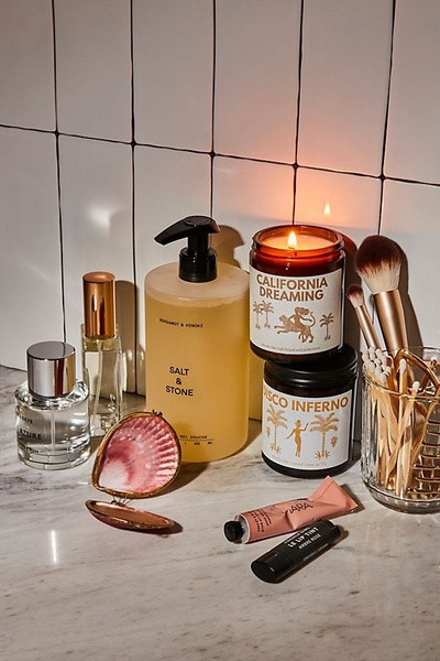 A high-quality still life arrangement featuring skincare products, scented candles, and makeup brushes on a marble surface, creating an elegant lifestyle atmosphere.