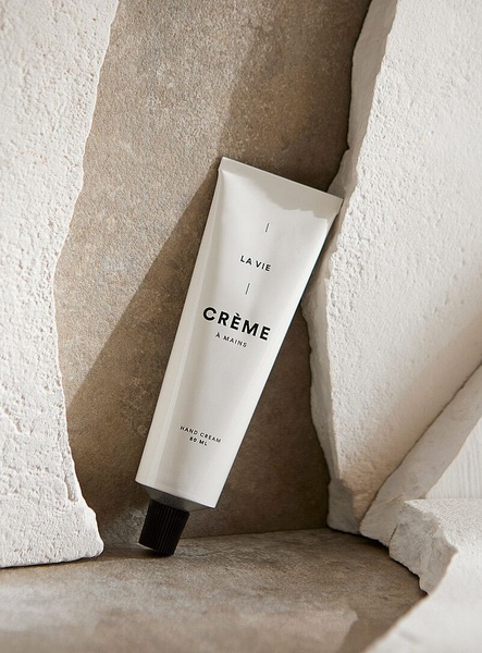 A high-end, studio-lit photograph of a hand cream tube nestled within textured stone, emphasizing luxury and organic textures.