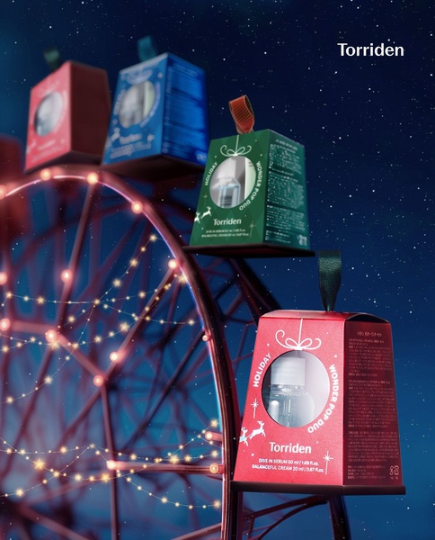 A festive product showcase featuring skincare serums presented as hanging ornaments on a stylized Ferris wheel against a starry night background.