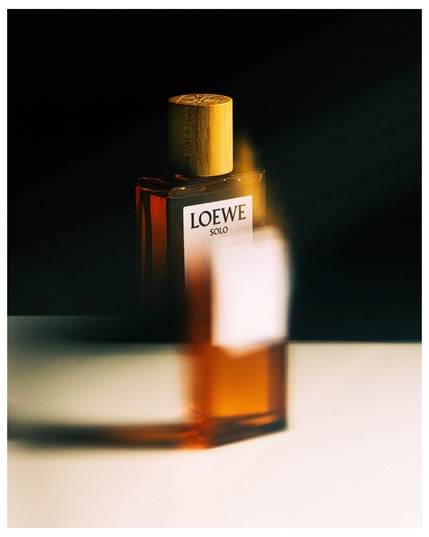 A high-end, artistic product shot featuring a single perfume bottle with deep shadows, motion blur, and a moody, atmospheric lighting style.