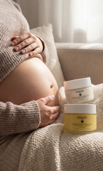 A close-up, serene shot of a pregnant woman's belly with two jars of pregnancy stretch marks cream placed alongside, set in a cozy indoor environment.
