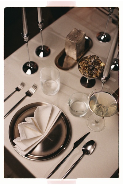 A high-end, top-down view of a formal table setting featuring neutral tones, glassware, and silver accents to create a luxurious dining mood.
