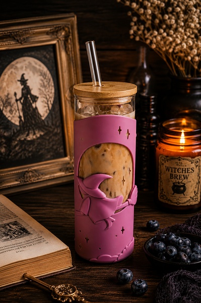A high-quality lifestyle shot featuring a witch-themed glass tumbler in a dark, moody, and aesthetic setting.